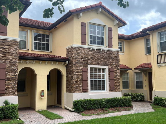 Front view of a two-story house with stone accents and red tile roofing.