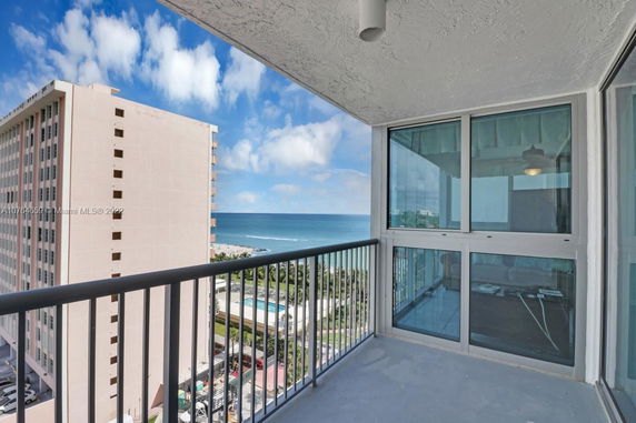 View from a balcony overlooking the ocean and nearby buildings.