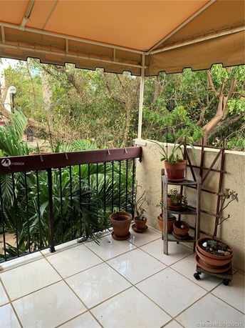 Balcony view with potted plants and partial view of surrounding greenery.