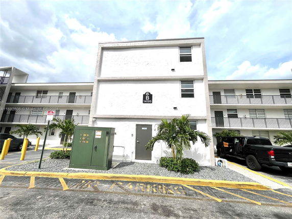 Front view of a three-story apartment building with balconies.
