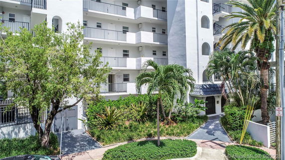 Exterior view of a multi-story residential building with balconies and greenery.