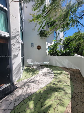 Outdoor view of a building wall with windows and patio area.