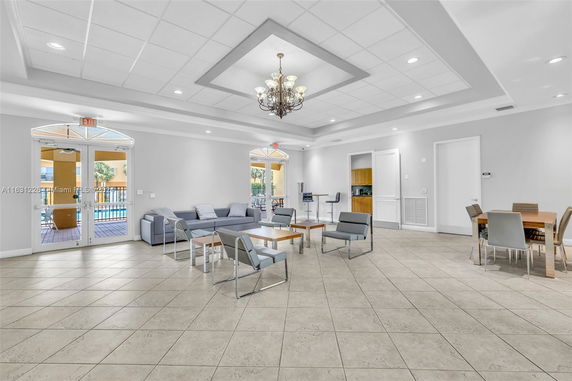Spacious indoor area with seating arrangements, a chandelier, and multiple tables.