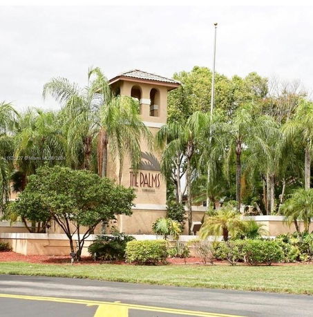 Front view of a building with a tower and palm trees.
