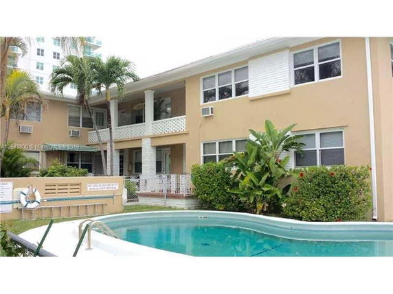 Front view of a two-story house with a swimming pool in front.