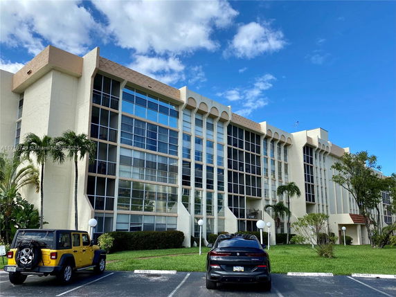 Front view of a multi-story apartment building with large windows.