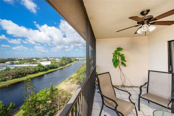 Outdoor balcony with chairs overlooking a river and surrounding landscape.