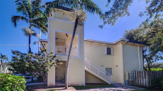 Front view of a yellow two-story building with an external staircase.