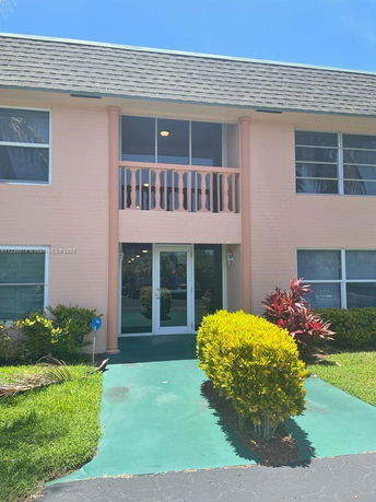 Front view of a two-story building with a balcony and large windows.