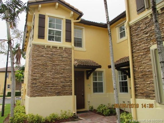 Front view of a two-story townhouse with stone accents and a brown door.