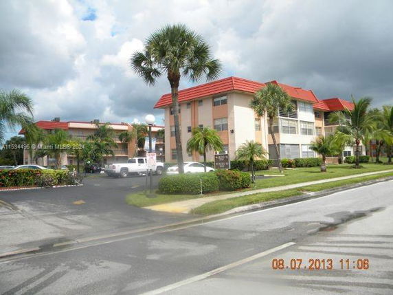 Front view of a multi-story building with a red roof and palm trees.