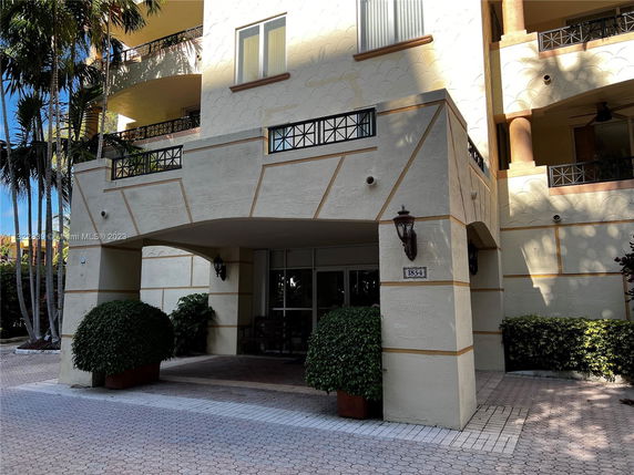 Front view of a multi-story building with decorative railings and an entrance patio.