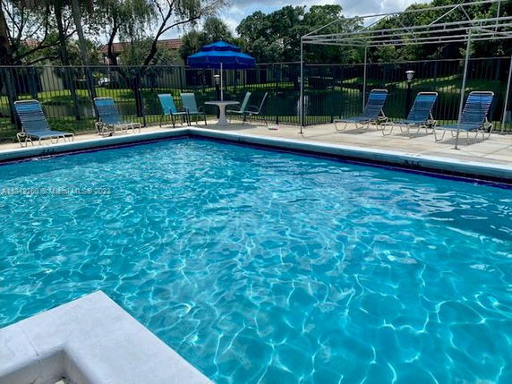 Outdoor swimming pool with surrounding lounge chairs and umbrellas.
