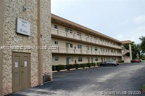Front view of a multi-story building with balconies and parking area.