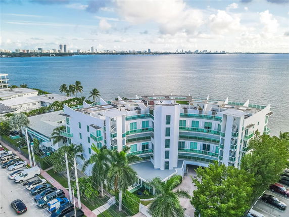 Aerial view of a multi-story waterfront building with curved balconies and glass accents.