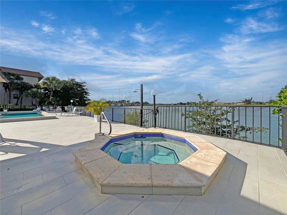 Outdoor area with a pool and jacuzzi overlooking a body of water.