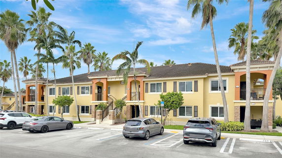 Front view of a two-story building with balconies and parking spaces in front.