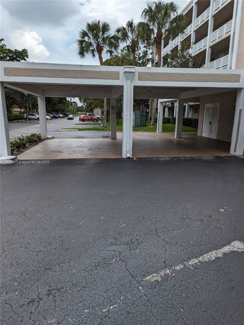 Covered parking area in front of a multi-story building.