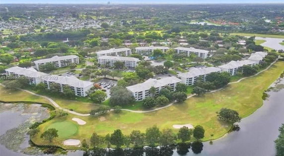 Aerial view of a residential complex surrounded by greenery and water bodies.