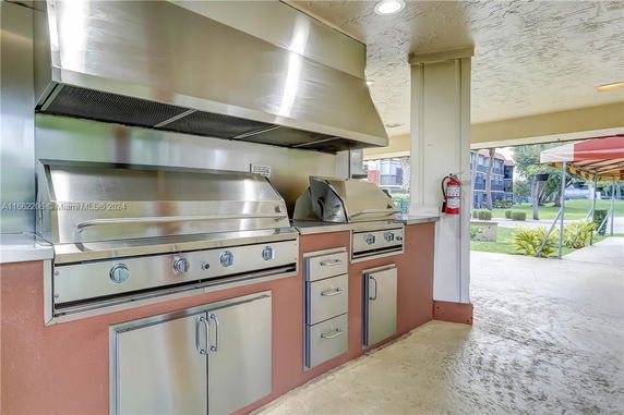 Outdoor kitchen area with stainless steel grills and ventilation hood.