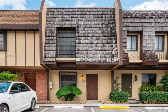 Front view of a townhouse with wooden detailing and shingle roofing.