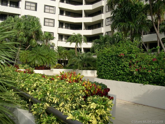 Front view of a multi-story building with balconies and a landscaped garden.