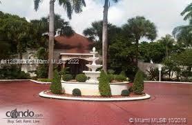 Front view of a building with a fountain and landscaped circular driveway.
