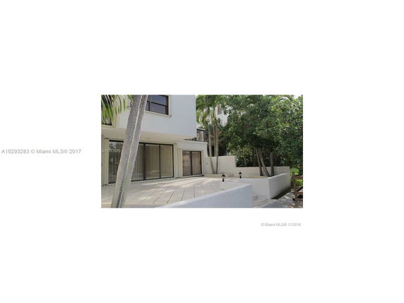 View of a modern two-story building with large windows and a tiled patio area.