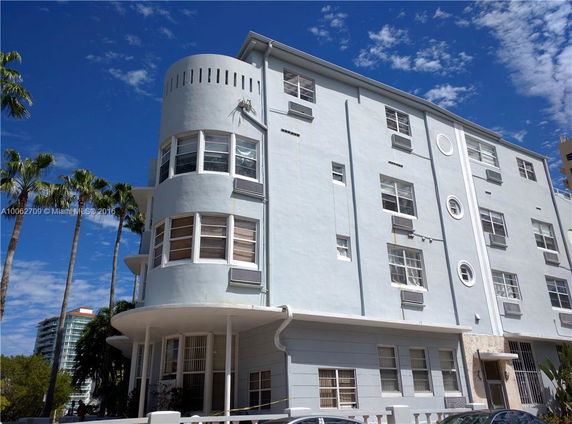 Front view of a multi-story building with rounded corner and multiple windows.