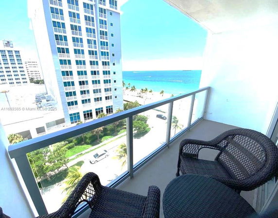 View from a balcony overlooking the ocean and nearby buildings.