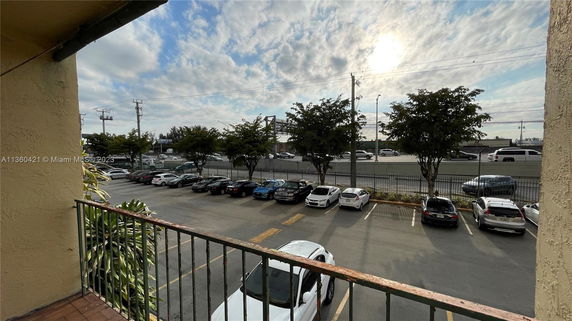 View of an outdoor parking area with several cars parked and a road in the background.
