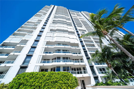 Upward view of a tall residential building with multiple balconies and glass windows.