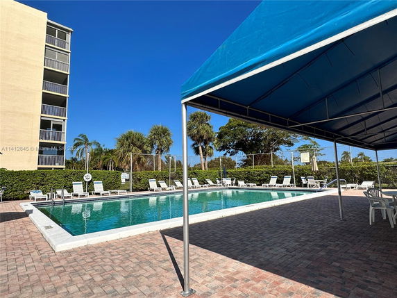 View of an outdoor swimming pool with a nearby multi-story building.
