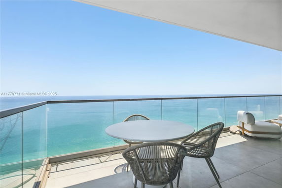 Balcony view with seating area overlooking the ocean.
