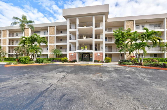 Front view of a multi-story building with balconies and greenery.
