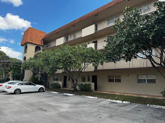 Front view of a three-story building with a red-tiled roof and a parking area.