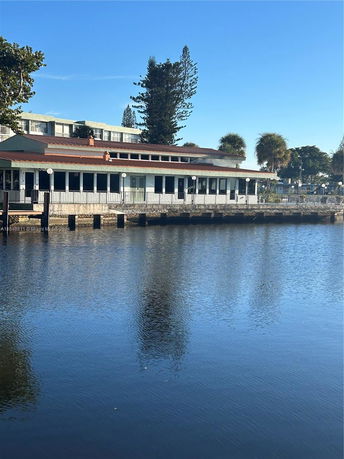 Front view of a waterside building with a sloped roof and multiple glass doors.