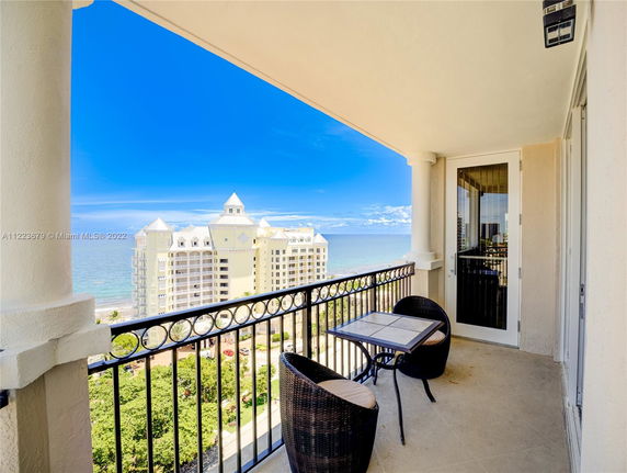 Balcony view of a multi-story beachfront building with a clear ocean backdrop.