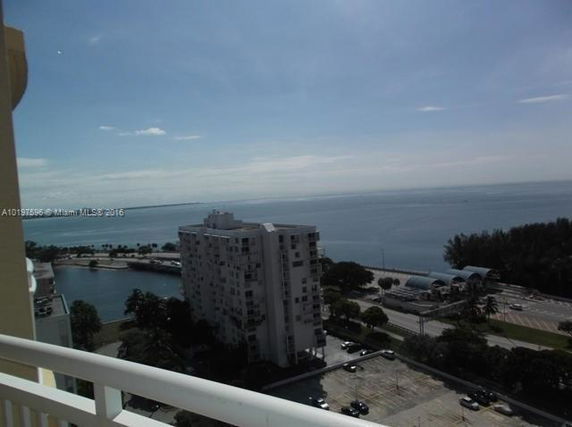 Panoramic view from a high-rise balcony overlooking a body of water and surrounding buildings.