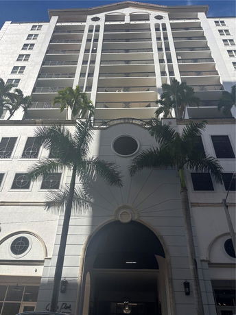 Front view of a multi-story residential building with balconies and arched entrance.