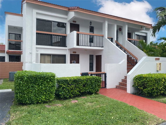 Front view of a two-story residential building with balconies and stairs leading to the entrances.