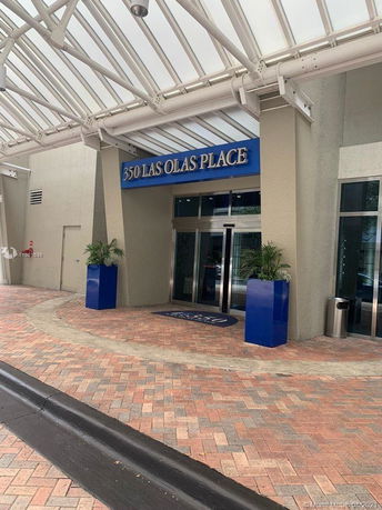 Entrance view of a commercial building with a glass canopy and revolving doors.