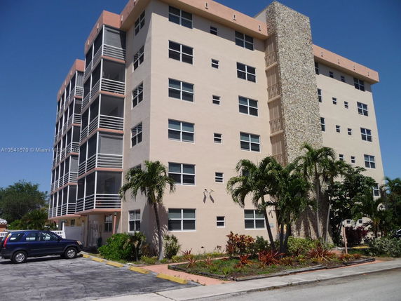 Front view of a multi-story residential building with balconies and a stone accent wall.