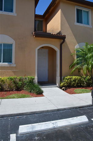 Front view of a two-story house with arched doorway and windows.