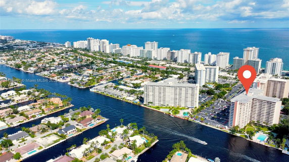 Aerial view of waterfront high-rise buildings near a canal with a blue ocean in the background.