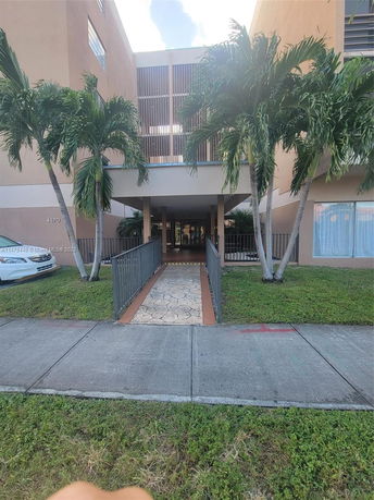 Front view of a multi-story building with a pathway and palm trees.