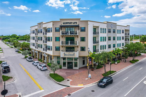 Front view of a multi-story building labeled Mainstreet Lofts with balconies and ground-floor retail units.