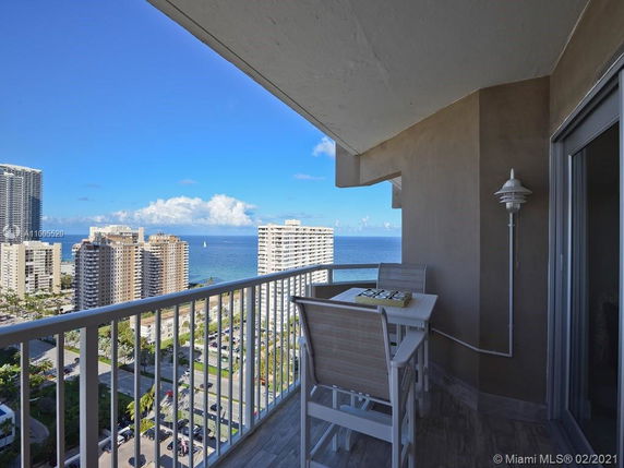 Balcony view overlooking high-rise buildings and ocean.
