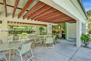 Outdoor seating area with tables and chairs under a wooden roof.