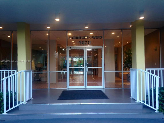 Front view of the entrance to Admiral Towers, featuring glass doors and railing on both sides of the stairs.